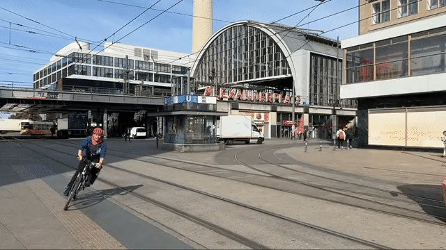GIF vom Vorplatz des Bahnhofs Alexanderplatz. Regionalzüge ,S-Bahnen, Straßenbahnen, Radfahrer und Fußgänger bewegen sich schnell.